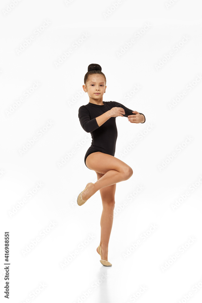 gymnast girl standing in ballet pose on white background in studio