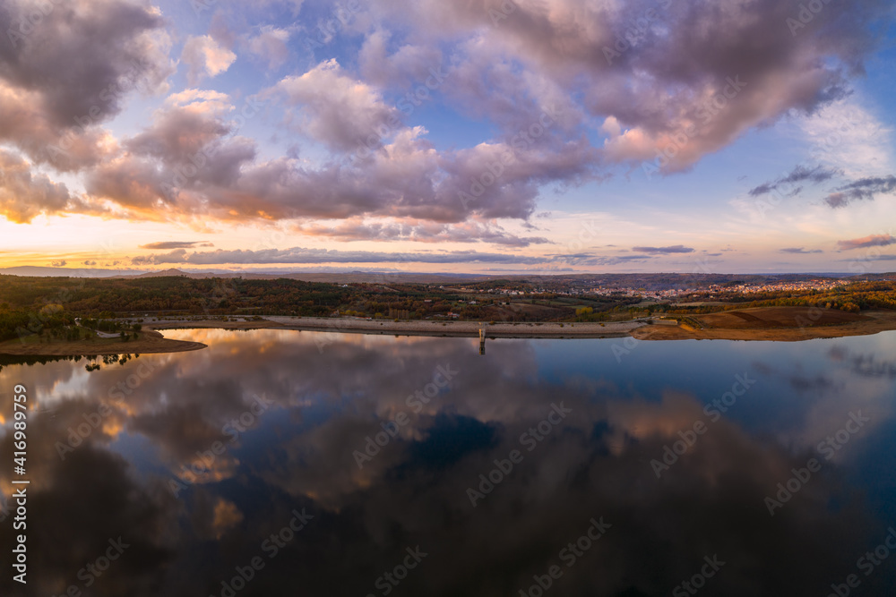 Obraz premium Drone aerial view of a lake reservoir of a dam with perfect reflection on the water of the sunset in Sabugal, Portugal