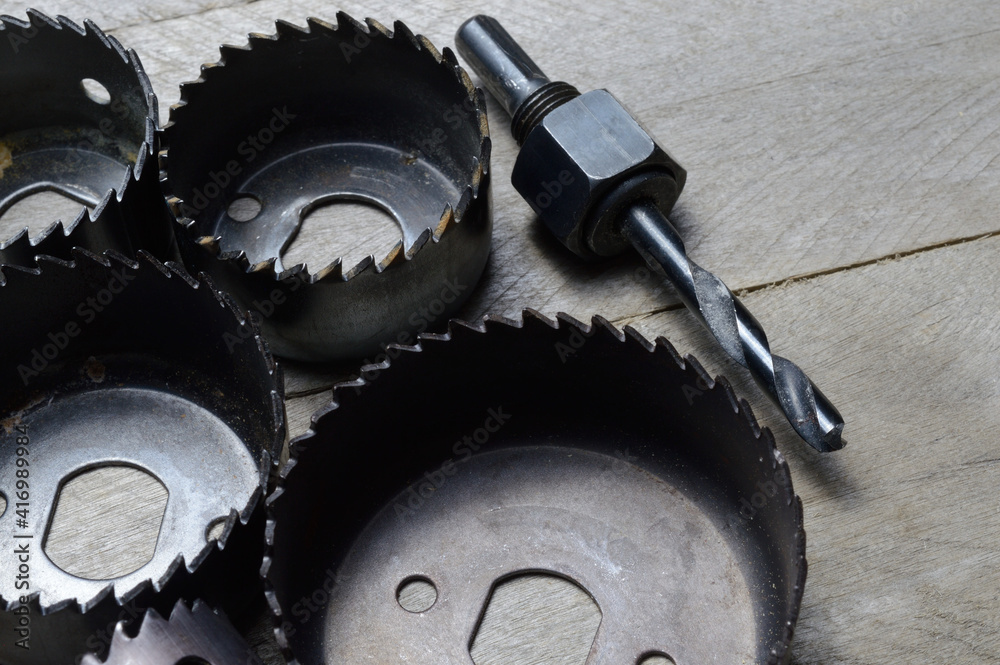 a set of old crowns for drilling a tree lies on a plank, wooden background. close-up.