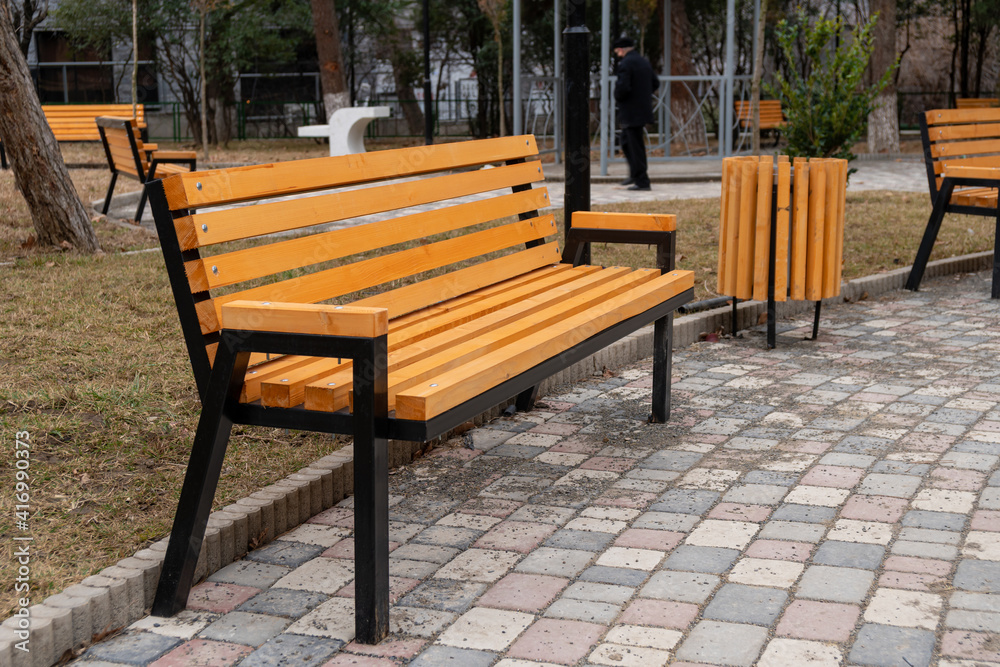 Wooden bench in the city park, place for relaxation Wooden bench in the city park, place for relaxation