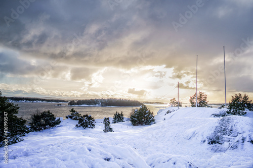 A view of the Stockholm archipelago. A snowy landscape with some flagpoles and a power line that leads electricity to the islands via a submarine cable.