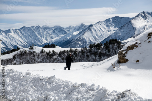 photographer in a black jacket against the background of mountains and gorges against the background of snow