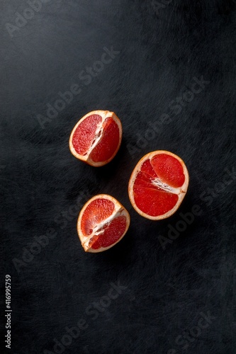three pieces of grapefruit on a black scratched background