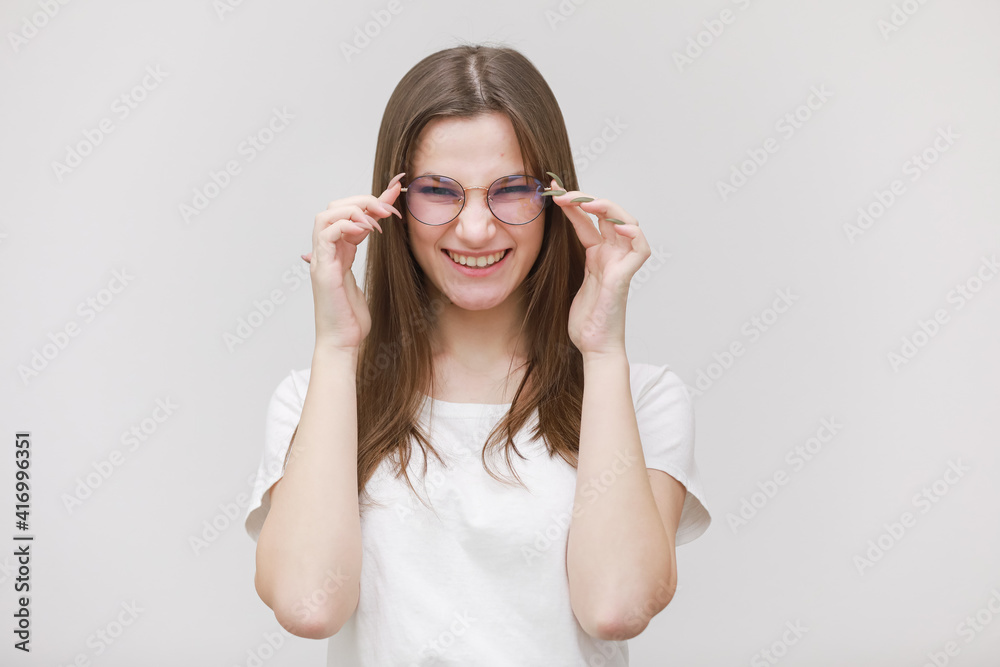 pretty teenage girl in glasses having fun on a white background. female in white t shirt with long hair in studio pretty teenage girl in glasses having fun on a white background. female in white t shirt with long hair in studio