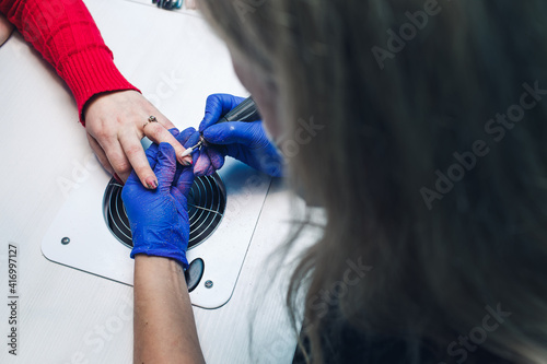 closeup of milling nails in a beauty salon. A woman gets a manicure for her nails. Beautician polishes customer's nails photo