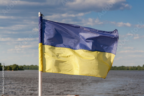 Ukrainian flag against the background of the river and sky