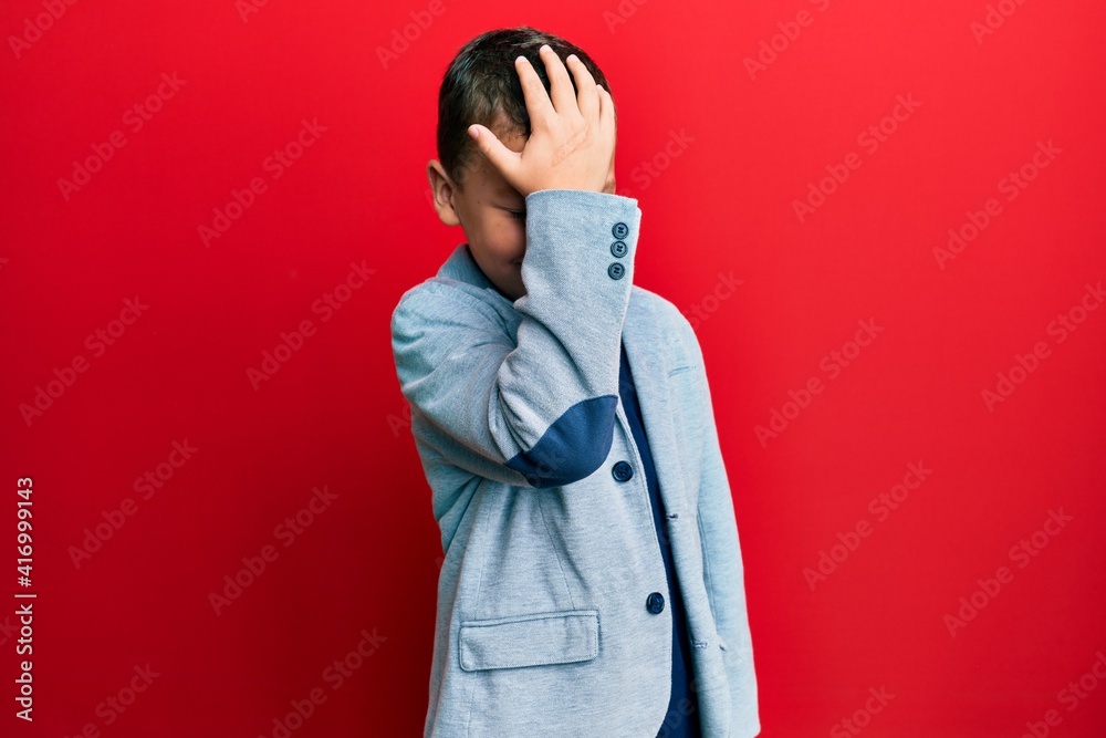 Little kid boy wearing elegant business jacket surprised with hand on head for mistake, remember error. forgot, bad memory concept. Little kid boy wearing elegant business jacket surprised with hand on head for mistake, remember error. forgot, bad memory concept.