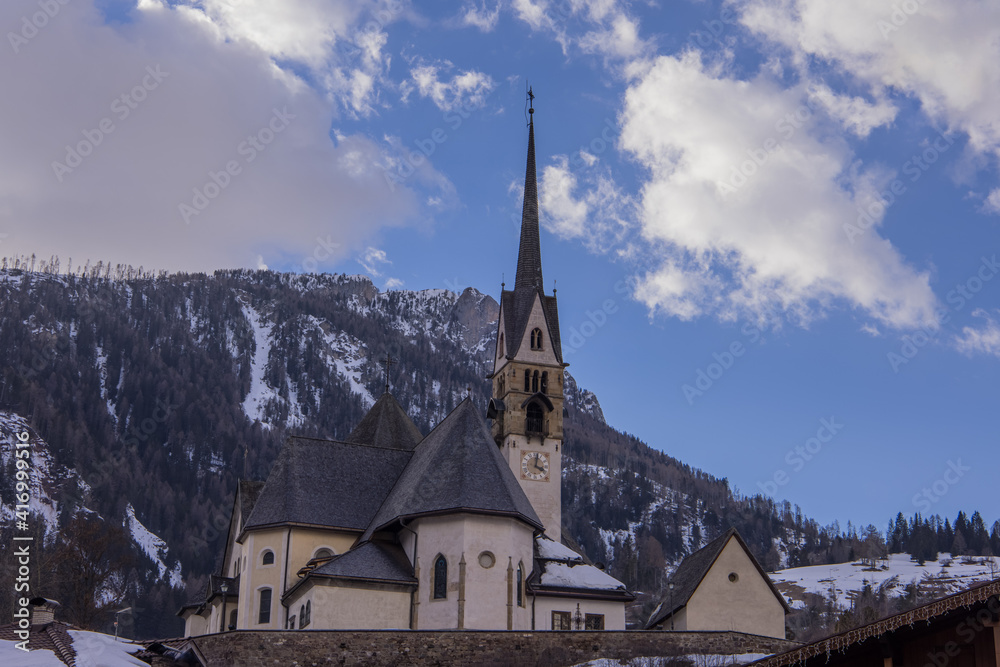 Church on a hill in the centre of the city of Moena in the italian dolomites in valley of Fassa on a warm winter day.