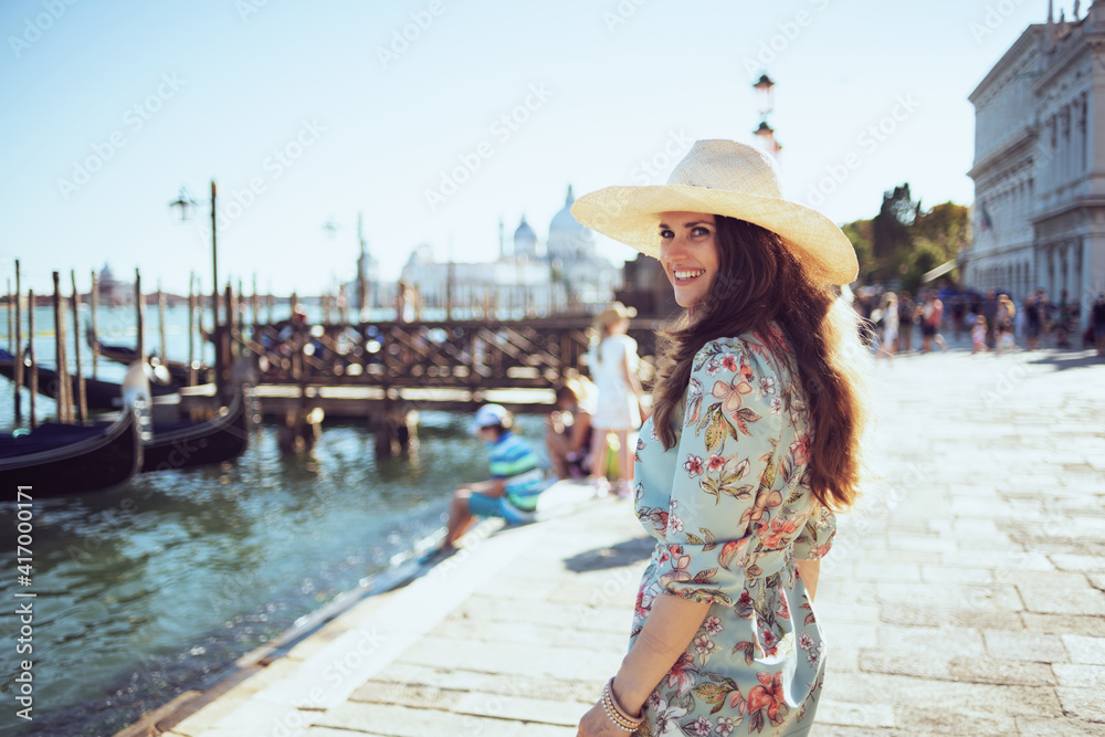 smiling modern traveller woman in floral dress sightseeing