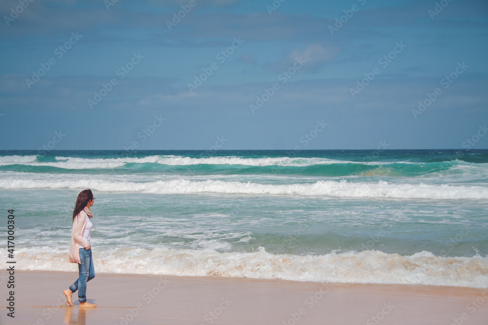 Happy carefree woman enjoying beautiful sunset on the beach. Young woman silhouette sitting and watching on the sun. Vacation and travel. Summer inspiration. Have fun in the sea