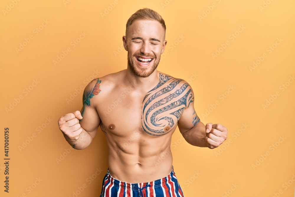 Fototapeta premium Young caucasian man wearing swimwear shirtless excited for success with arms raised and eyes closed celebrating victory smiling. winner concept.
