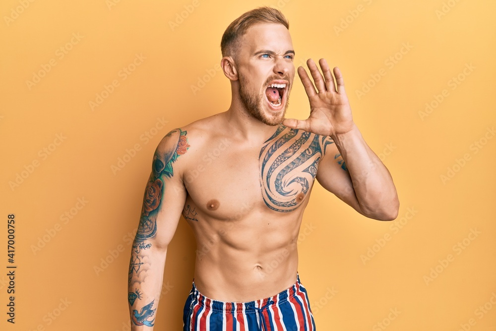 Young caucasian man wearing swimwear shirtless shouting and screaming loud to side with hand on mouth. communication concept.
