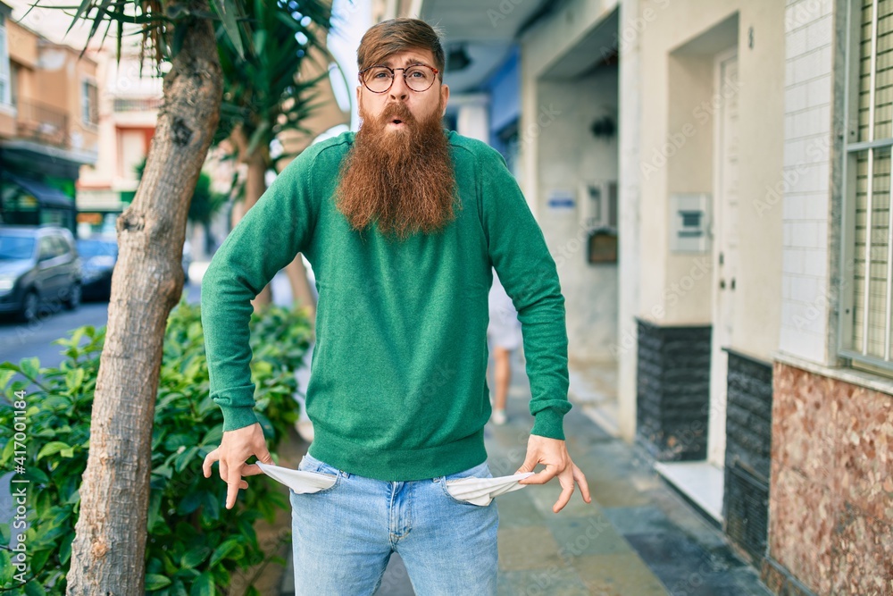 Young irish man with sad expression showing his empty pockets jeans at the city. Young irish man with sad expression showing his empty pockets jeans at the city.
