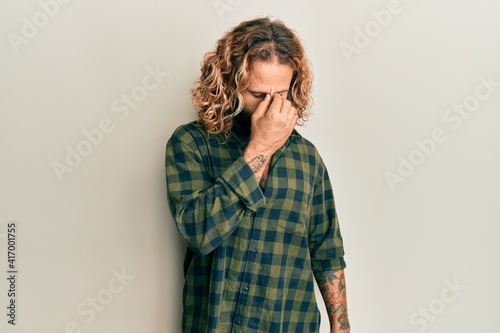 Handsome man with beard and long hair wearing casual clothes tired rubbing nose and eyes feeling fatigue and headache. stress and frustration concept.