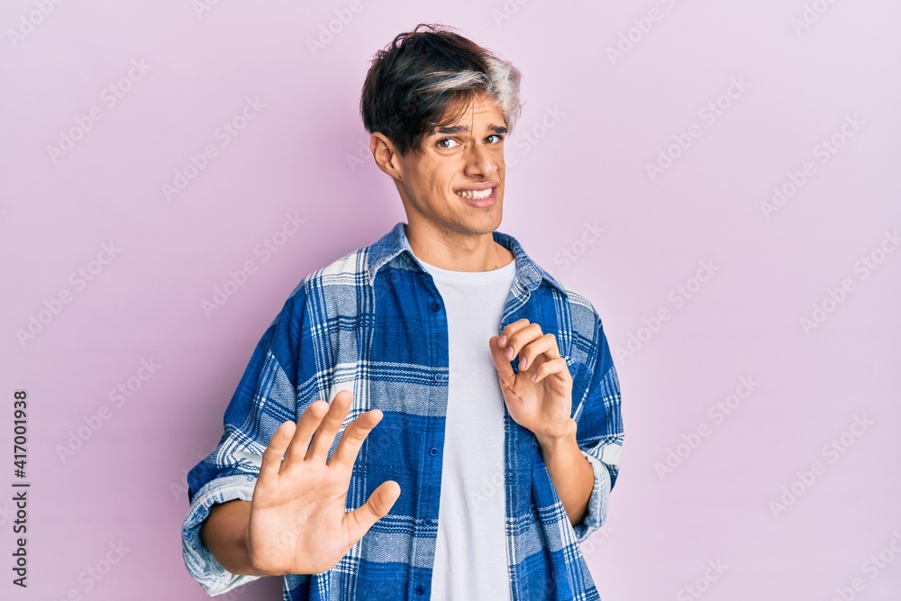 Young hispanic man wearing casual clothes disgusted expression, displeased and fearful doing disgust face because aversion reaction. with hands raised Young hispanic man wearing casual clothes disgusted expression, displeased and fearful doing disgust face because aversion reaction. with hands raised