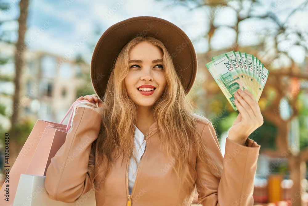 Young blonde girl shopping holding russian ruble banknotes at the city.