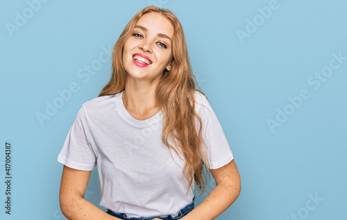 Young caucasian girl wearing casual white t shirt looking positive and happy standing and smiling with a confident smile showing teeth