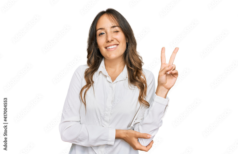 Young brunette woman wearing casual clothes smiling with happy face winking at the camera doing victory sign. number two. Young brunette woman wearing casual clothes smiling with happy face winking at the camera doing victory sign. number two.