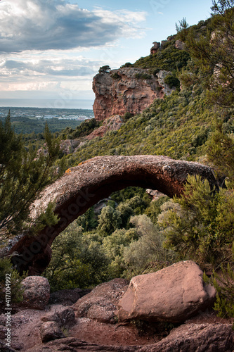 Paisaje de monta  a en el litoral mediterr  neo con un arco de roca en primer plano  bosque y arbustos y el mar y cielo de fondo