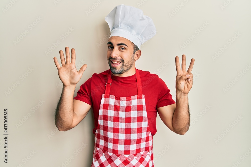 Young hispanic man wearing baker uniform showing and pointing up with fingers number eight while smiling confident and happy. Young hispanic man wearing baker uniform showing and pointing up with fingers number eight while smiling confident and happy.