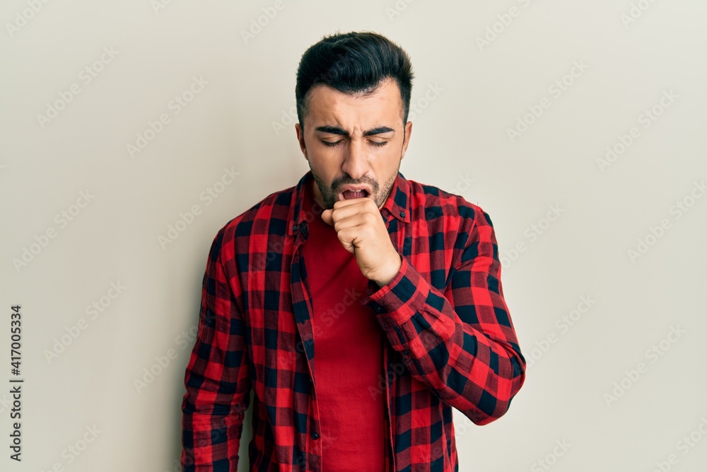 Young hispanic man wearing casual clothes feeling unwell and coughing as symptom for cold or bronchitis. health care concept. Young hispanic man wearing casual clothes feeling unwell and coughing as symptom for cold or bronchitis. health care concept.