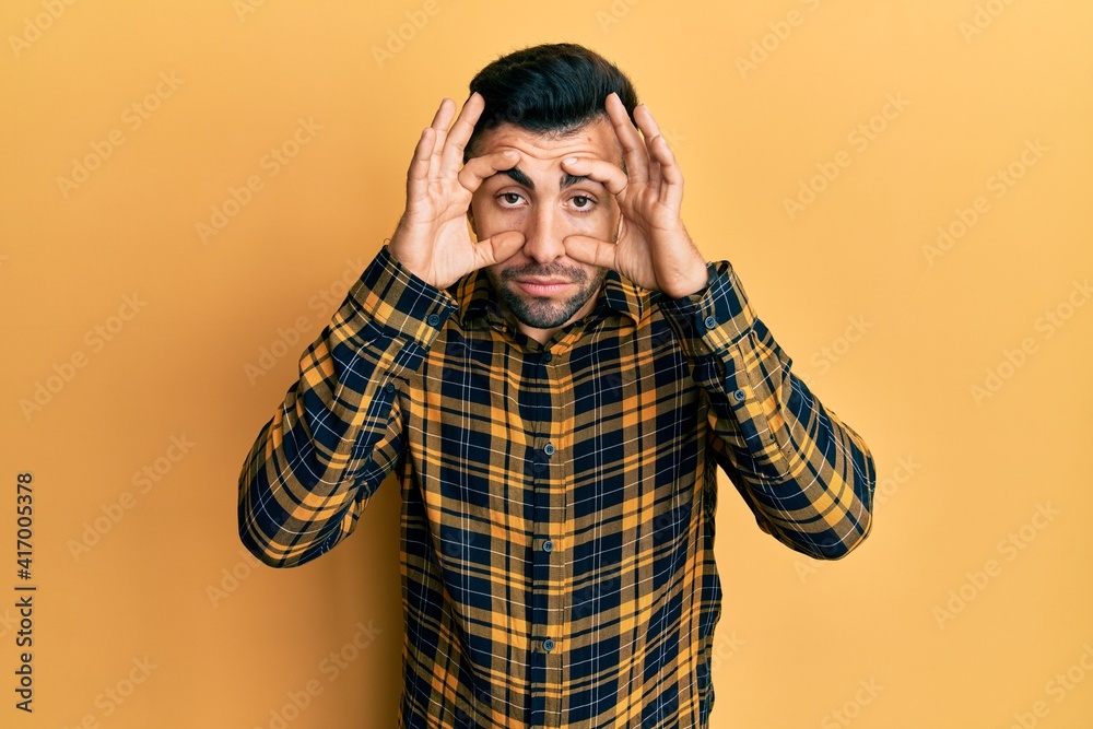 Young hispanic man wearing casual clothes trying to open eyes with fingers, sleepy and tired for morning fatigue Young hispanic man wearing casual clothes trying to open eyes with fingers, sleepy and tired for morning fatigue
