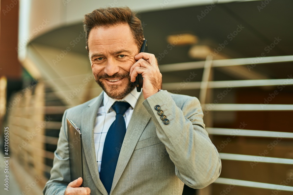 Middle age businessman smiling happy talking on the smartphone at the city. Middle age businessman smiling happy talking on the smartphone at the city.
