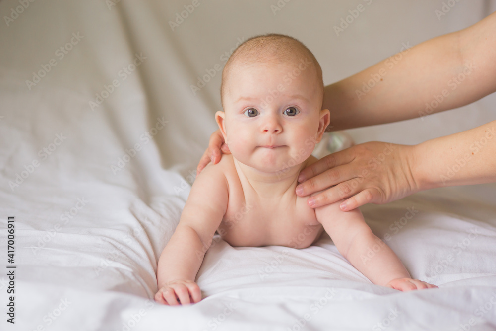 Happy infant girl doing baby massage by his mother at home. Newborn child about 5 months old Happy infant girl doing baby massage by his mother at home. Newborn child about 5 months old