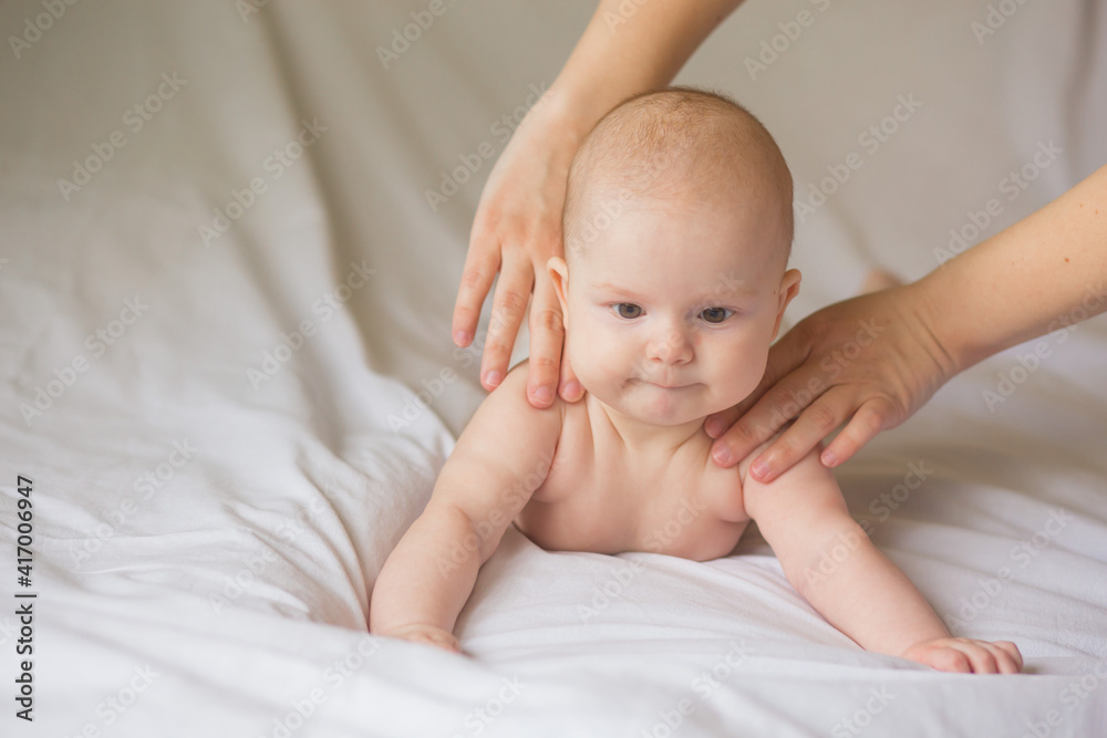 Happy infant girl doing baby massage by his mother at home. Newborn child about 5 months old Happy infant girl doing baby massage by his mother at home. Newborn child about 5 months old