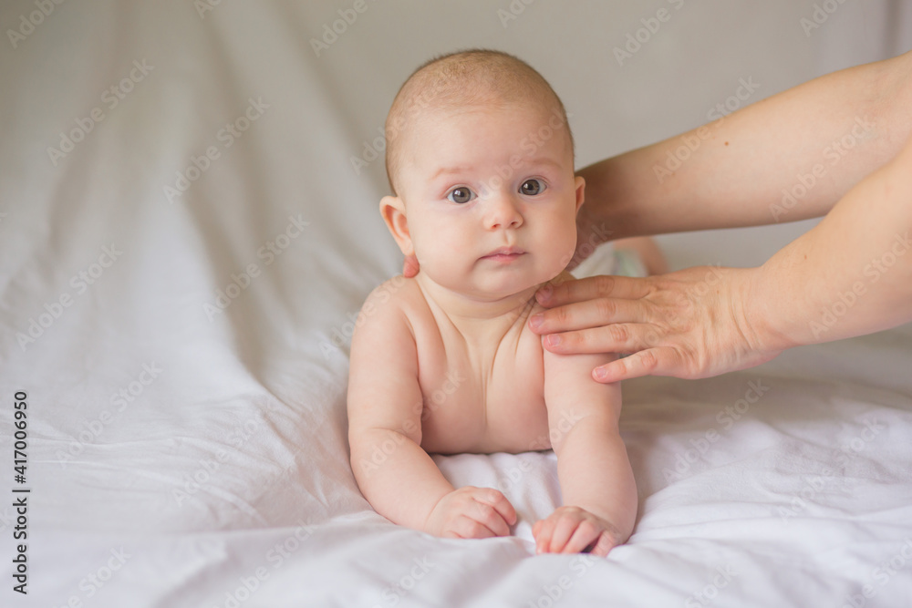 Happy infant girl doing baby massage by his mother at home. Newborn child about 5 months old Happy infant girl doing baby massage by his mother at home. Newborn child about 5 months old