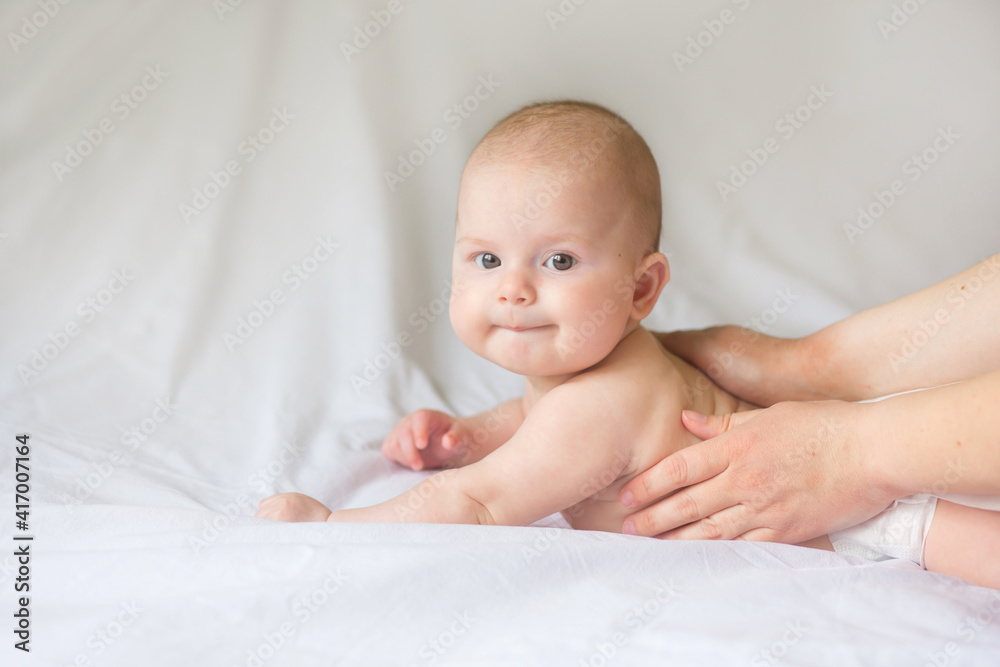 Happy infant girl doing baby massage by his mother at home. Newborn child about 5 months old Happy infant girl doing baby massage by his mother at home. Newborn child about 5 months old