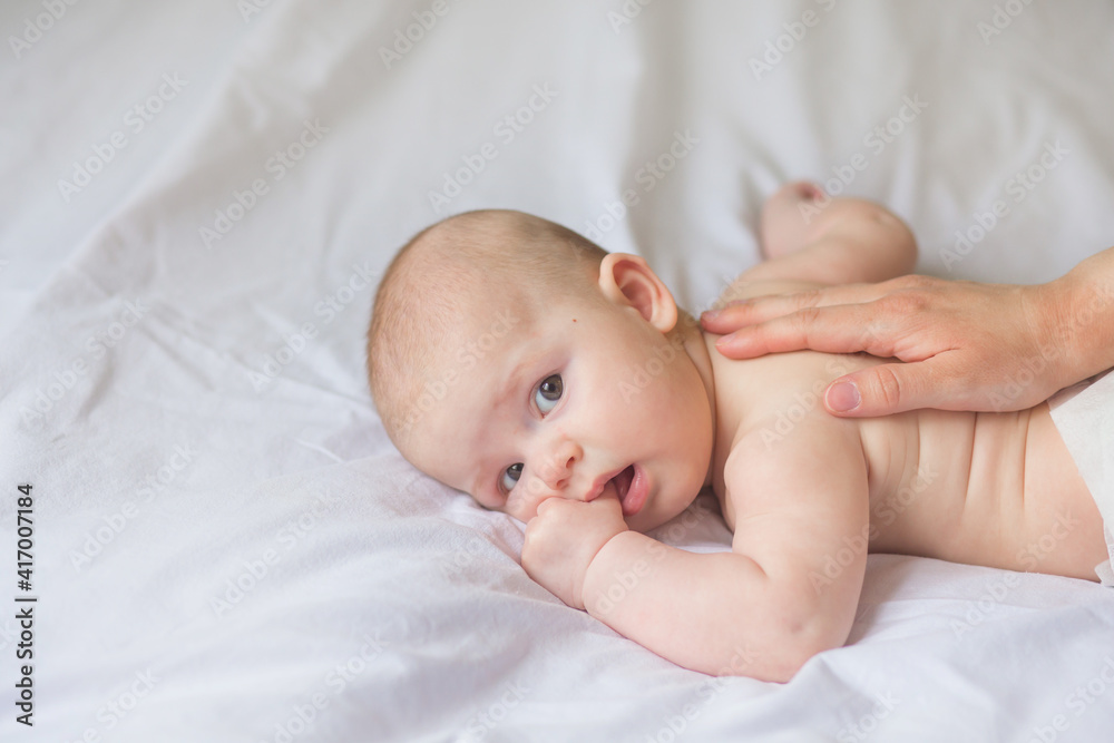 Happy infant girl doing baby massage by his mother at home. Newborn child about 5 months old Happy infant girl doing baby massage by his mother at home. Newborn child about 5 months old