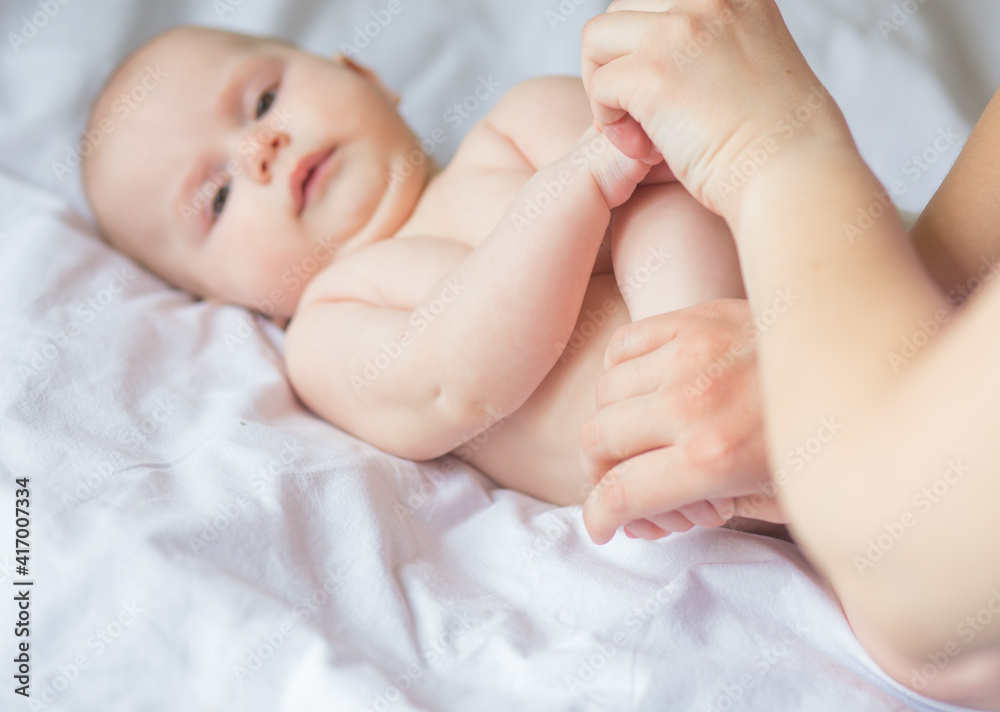 Happy infant girl doing baby massage by his mother at home. Newborn child about 5 months old Happy infant girl doing baby massage by his mother at home. Newborn child about 5 months old