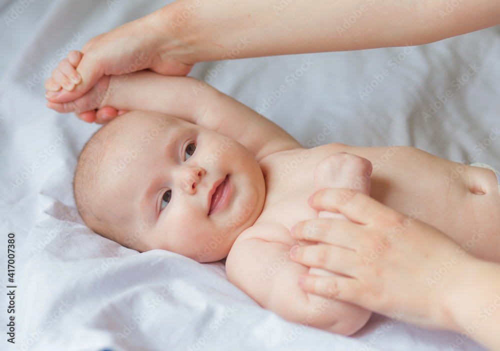 Happy infant girl doing baby massage by his mother at home. Newborn child about 5 months old Happy infant girl doing baby massage by his mother at home. Newborn child about 5 months old