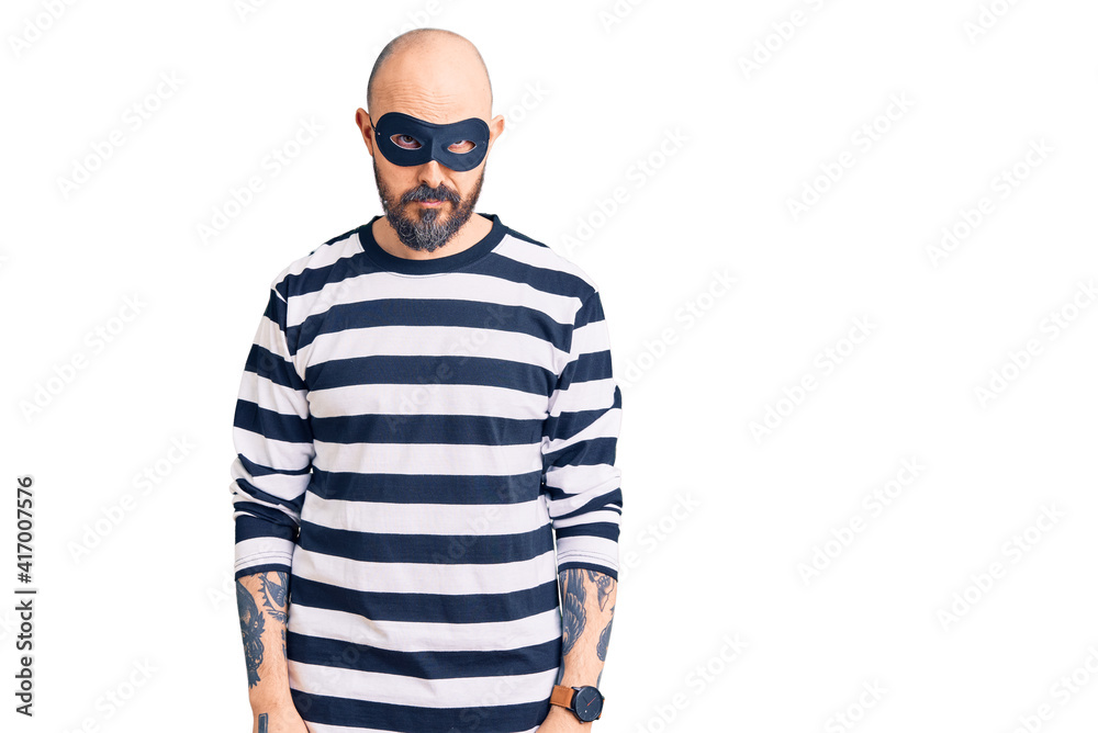 Young handsome man wearing burglar mask skeptic and nervous, frowning upset because of problem. negative person. Young handsome man wearing burglar mask skeptic and nervous, frowning upset because of problem. negative person.