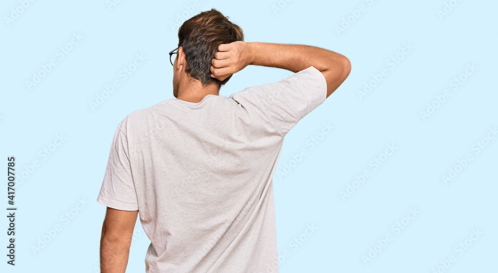 Handsome caucasian man wearing casual clothes and glasses backwards thinking about doubt with hand on head Handsome caucasian man wearing casual clothes and glasses backwards thinking about doubt with hand on head