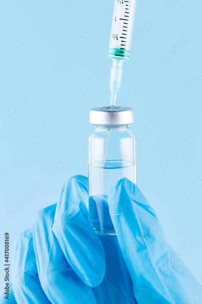 Hand filling syringe with medication. Robotic arm in surgical glove holding syringe with Covid-19 vaccine. Vaccination concept Hand filling syringe with medication. Robotic arm in surgical glove holding syringe with Covid-19 vaccine. Vaccination concept