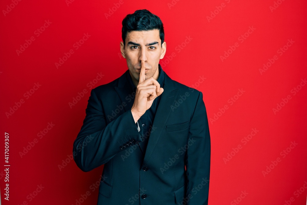 Handsome hispanic man wearing business clothes asking to be quiet with finger on lips. silence and secret concept. Handsome hispanic man wearing business clothes asking to be quiet with finger on lips. silence and secret concept.