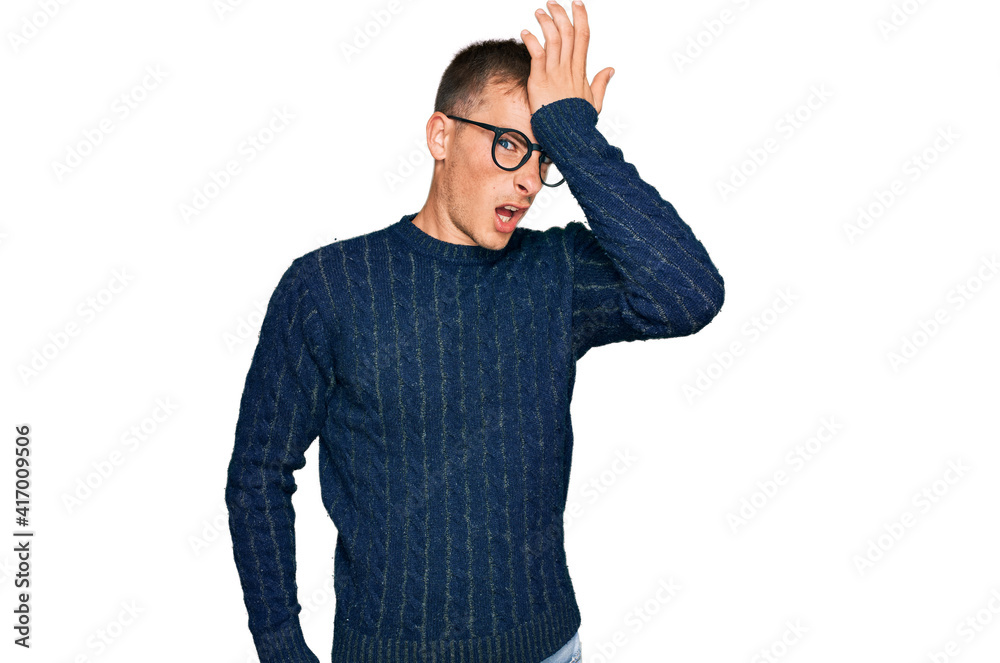 Fototapeta premium Young blond man wearing casual clothes and glasses surprised with hand on head for mistake, remember error. forgot, bad memory concept.