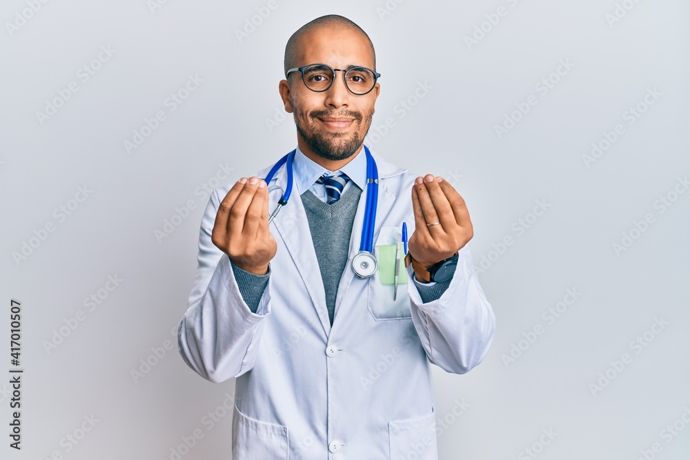 Hispanic adult man wearing doctor uniform and stethoscope doing money gesture with hands, asking for salary payment, millionaire business Hispanic adult man wearing doctor uniform and stethoscope doing money gesture with hands, asking for salary payment, millionaire business
