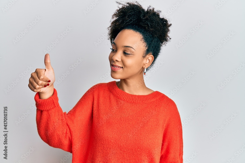 Young african american girl wearing casual clothes looking proud, smiling doing thumbs up gesture to the side Young african american girl wearing casual clothes looking proud, smiling doing thumbs up gesture to the side