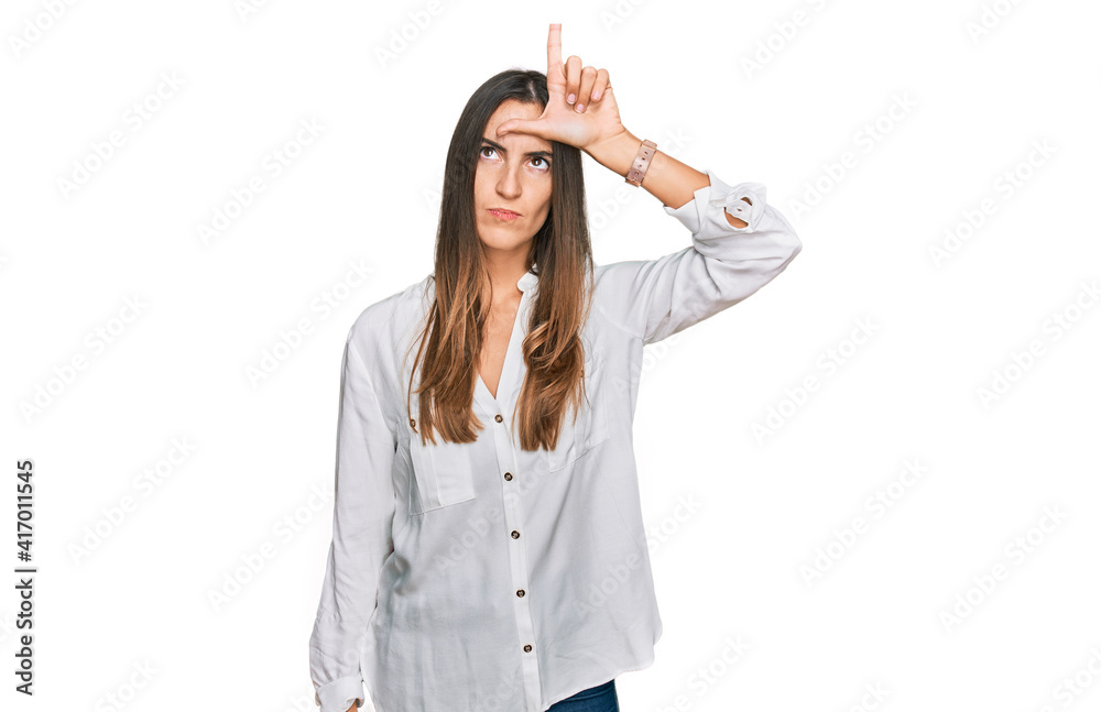 Young beautiful woman wearing casual clothes making fun of people with fingers on forehead doing loser gesture mocking and insulting. Young beautiful woman wearing casual clothes making fun of people with fingers on forehead doing loser gesture mocking and insulting.