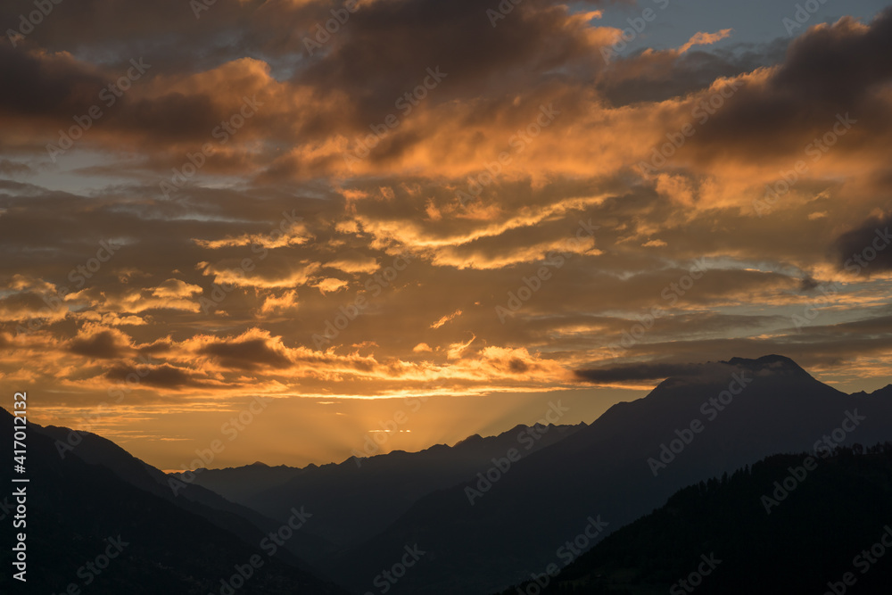 Aufgende Sonne über dem Goms bringt die Wolken zum Leuchten