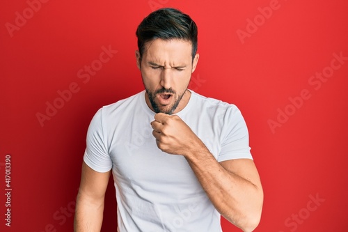 Young handsome man wearing casual white tshirt feeling unwell and coughing as symptom for cold or bronchitis. health care concept.