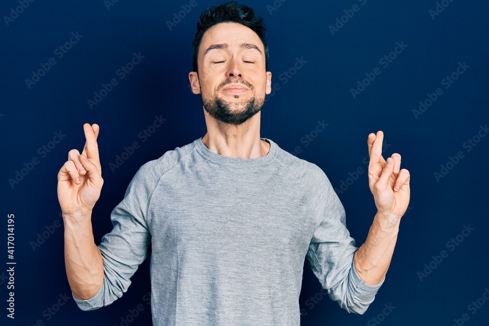 Young hispanic man wearing casual clothes gesturing finger crossed smiling with hope and eyes closed. luck and superstitious concept. Young hispanic man wearing casual clothes gesturing finger crossed smiling with hope and eyes closed. luck and superstitious concept.