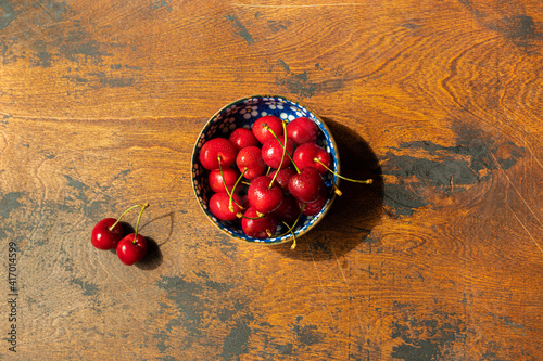 bowl with red cherries on wooden surface table, summer season, top view