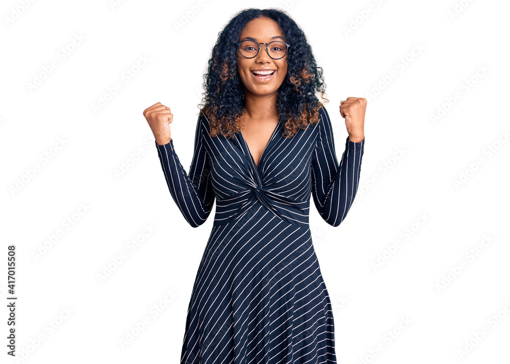 Young african american woman wearing casual clothes and glasses celebrating surprised and amazed for success with arms raised and open eyes. winner concept. Young african american woman wearing casual clothes and glasses celebrating surprised and amazed for success with arms raised and open eyes. winner concept.