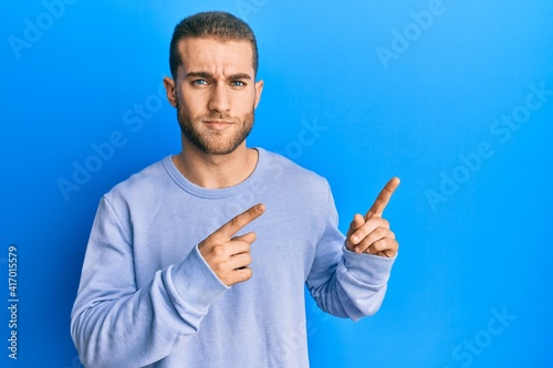 Young caucasian man pointing with fingers to the side skeptic and nervous, frowning upset because of problem. negative person.