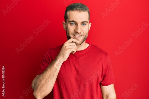 Young caucasian man wearing casual clothes smiling looking confident at the camera with crossed arms and hand on chin. thinking positive.