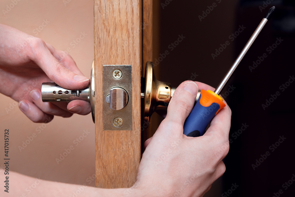 Door installation, worker Installs door knob, woodworker hands close up